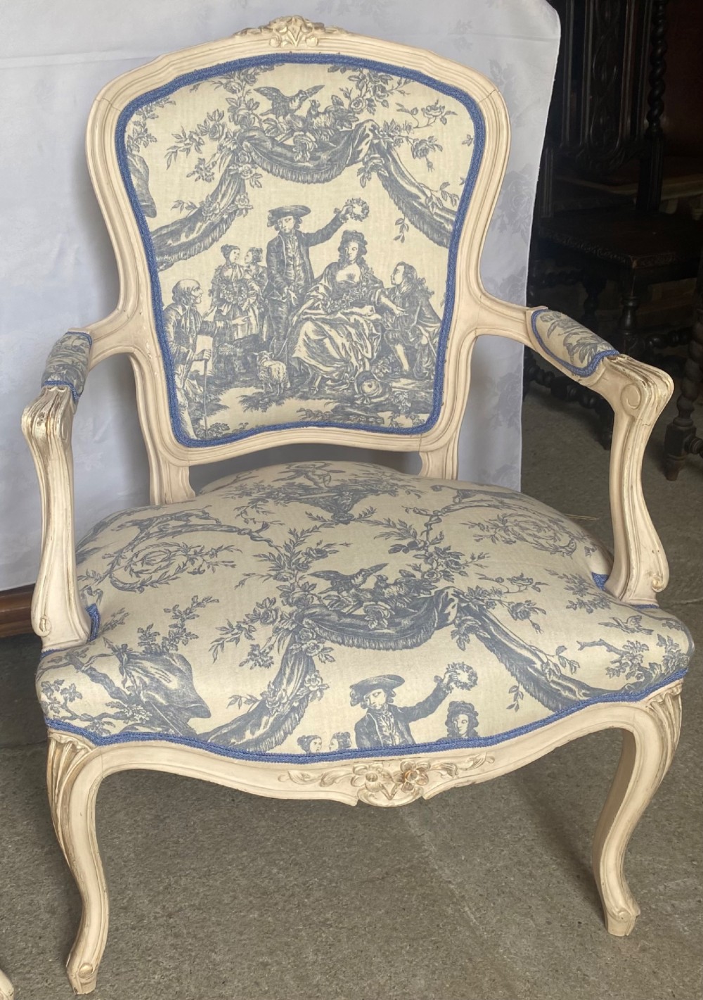 A pair of 19th-century French salon armchairs with off-white painted wooden frames, cabriole legs, and blue pastoral Toile de Jouy pattern upholstery. View VII
