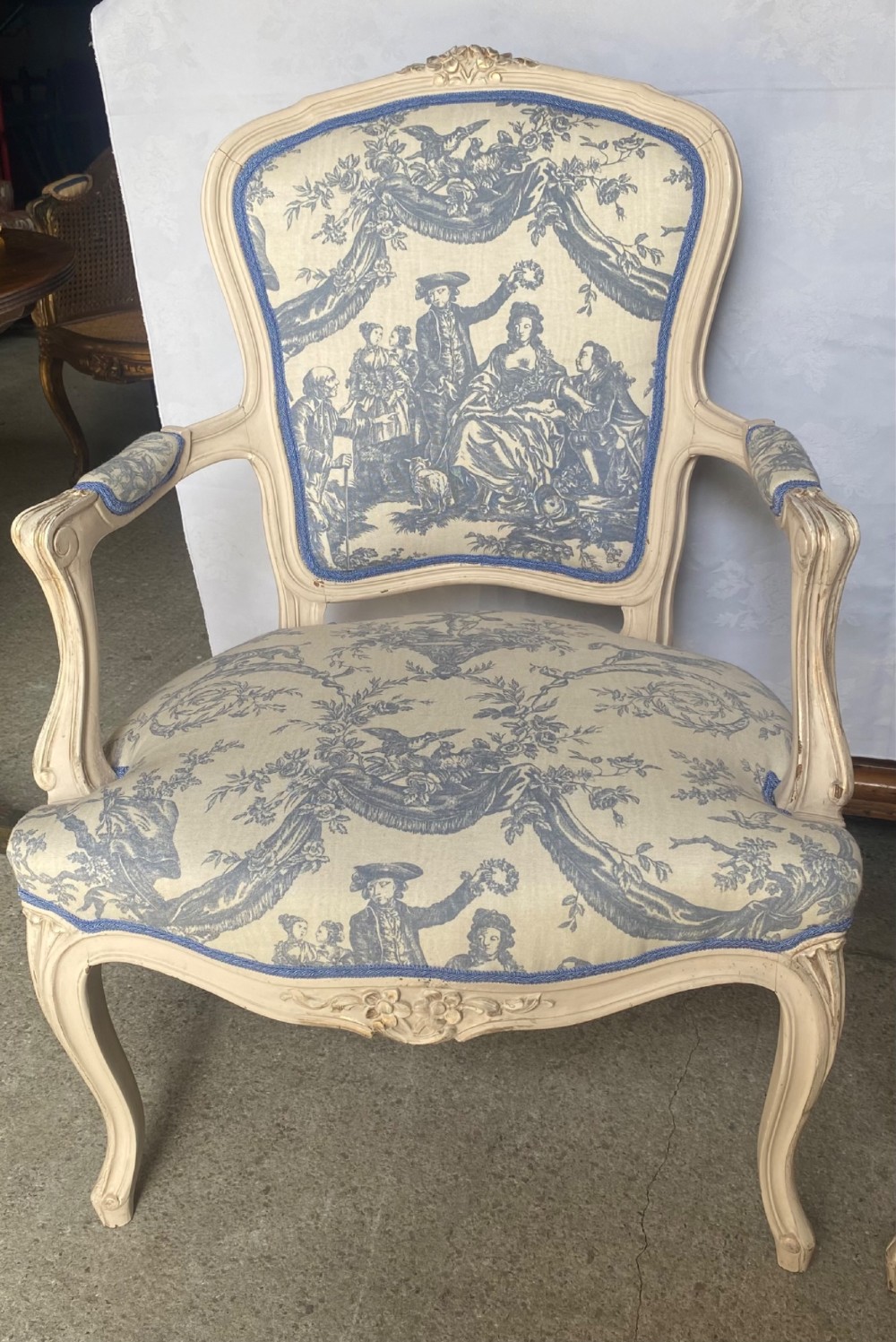 A pair of 19th-century French salon armchairs with off-white painted wooden frames, cabriole legs, and blue pastoral Toile de Jouy pattern upholstery. View VIII