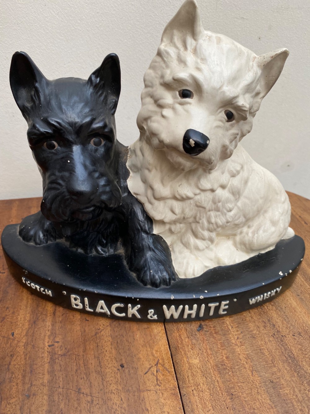 A vintage painted plaster advertising display figure featuring a black Scottish Terrier and a white West Highland White Terrier on a black base marked Scotch Black and White Whisky. View III