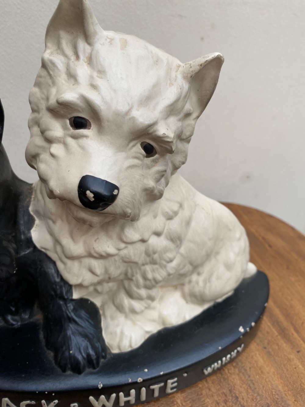 A vintage painted plaster advertising display figure featuring a black Scottish Terrier and a white West Highland White Terrier on a black base marked Scotch Black and White Whisky. View IV