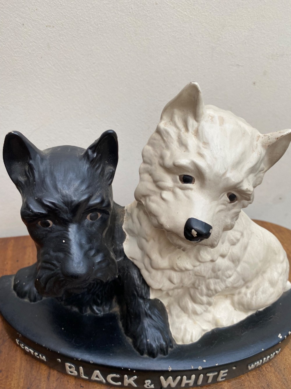 A vintage painted plaster advertising display figure featuring a black Scottish Terrier and a white West Highland White Terrier on a black base marked Scotch Black and White Whisky. View VI