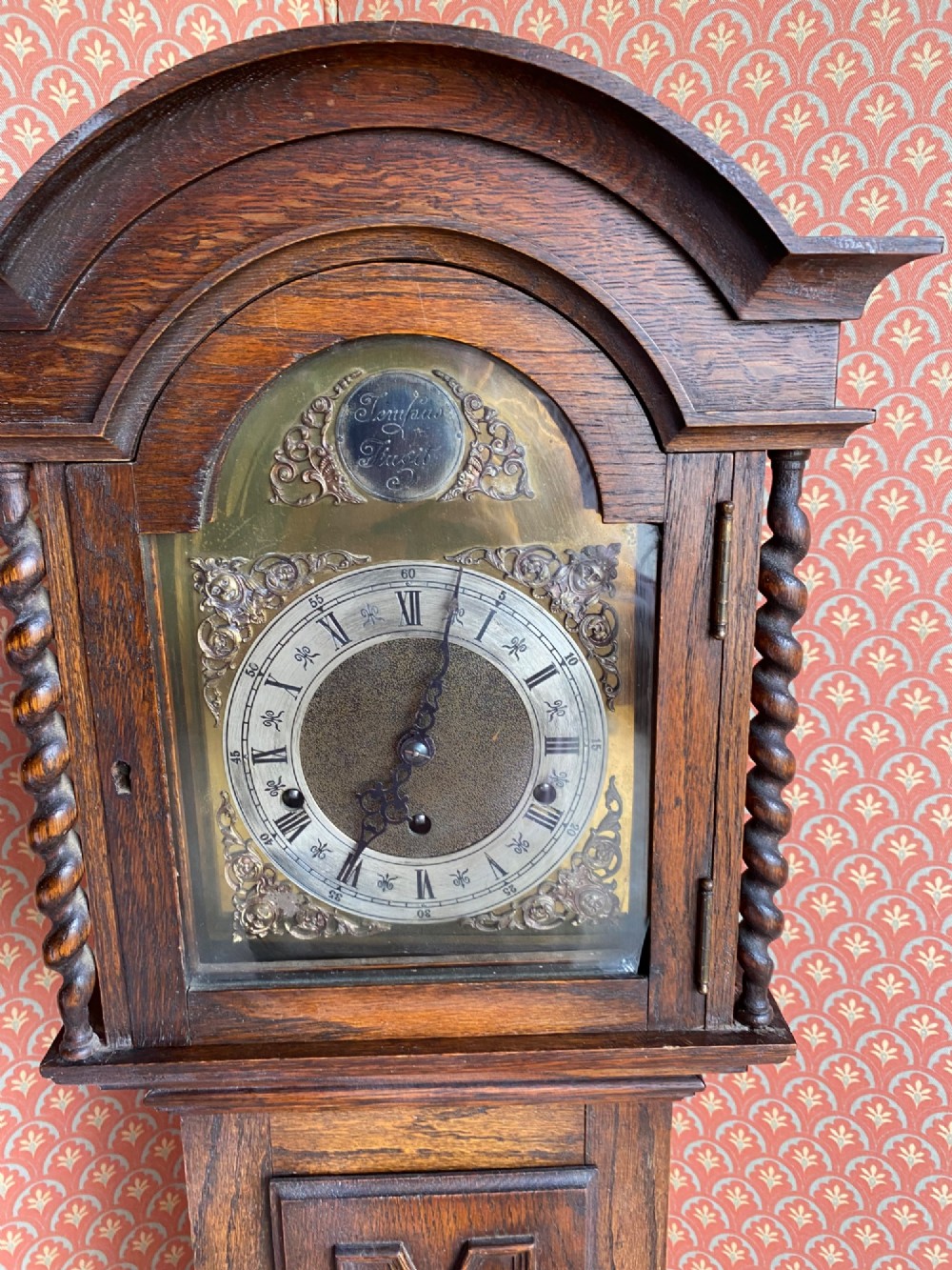 A Jacobean style oak grandmother clock featuring an arched top, barley twist columns, and a carved geometric panel door. View II