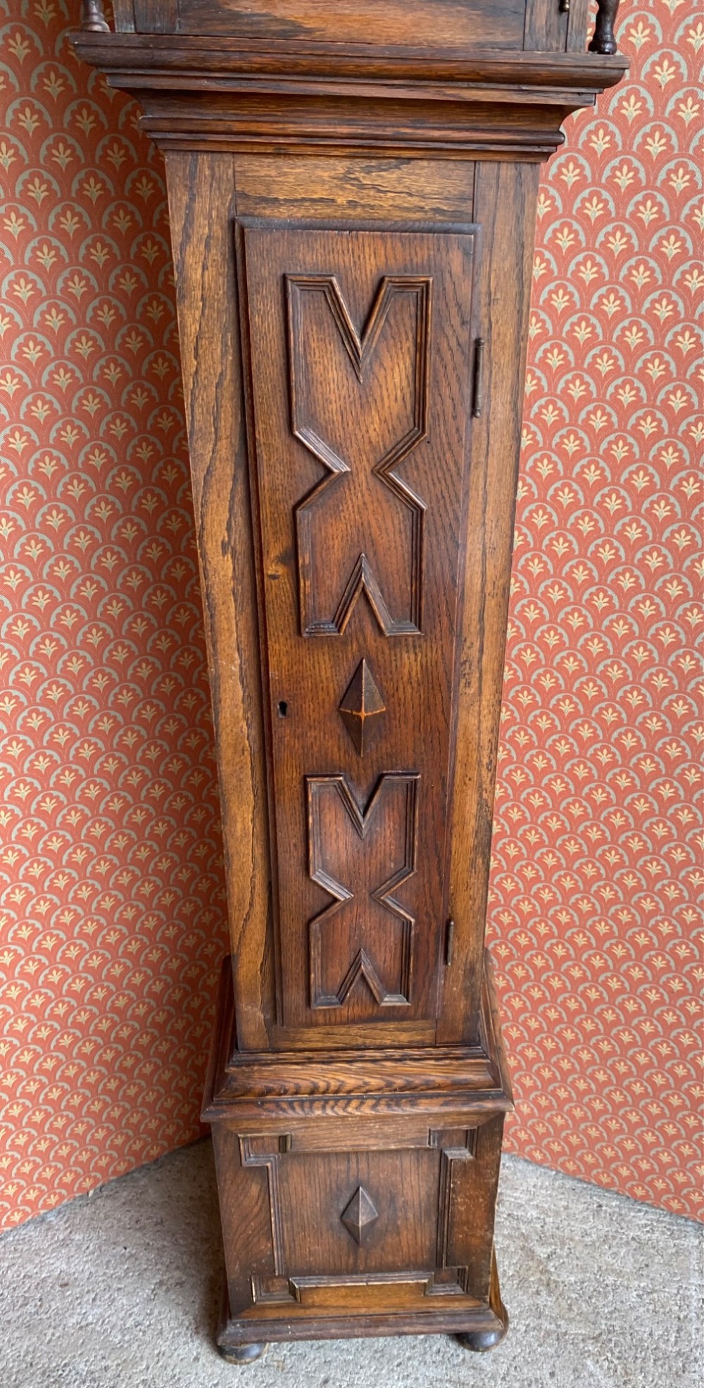 A Jacobean style oak grandmother clock featuring an arched top, barley twist columns, and a carved geometric panel door. View III
