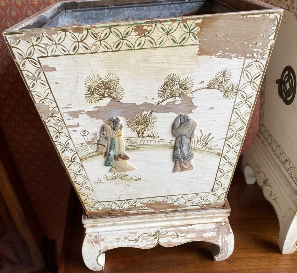 A pair of square cream painted wooden planters featuring raised figural motifs and banana palm tree designs on stepped bases with removable metal liners. View IV