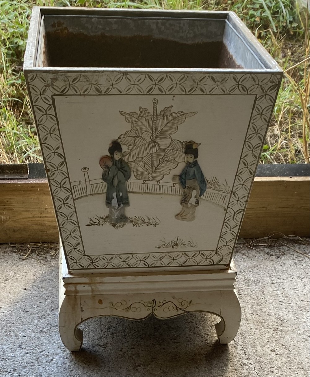 A pair of square cream painted wooden planters featuring raised figural motifs and banana palm tree designs on stepped bases with removable metal liners. View IX