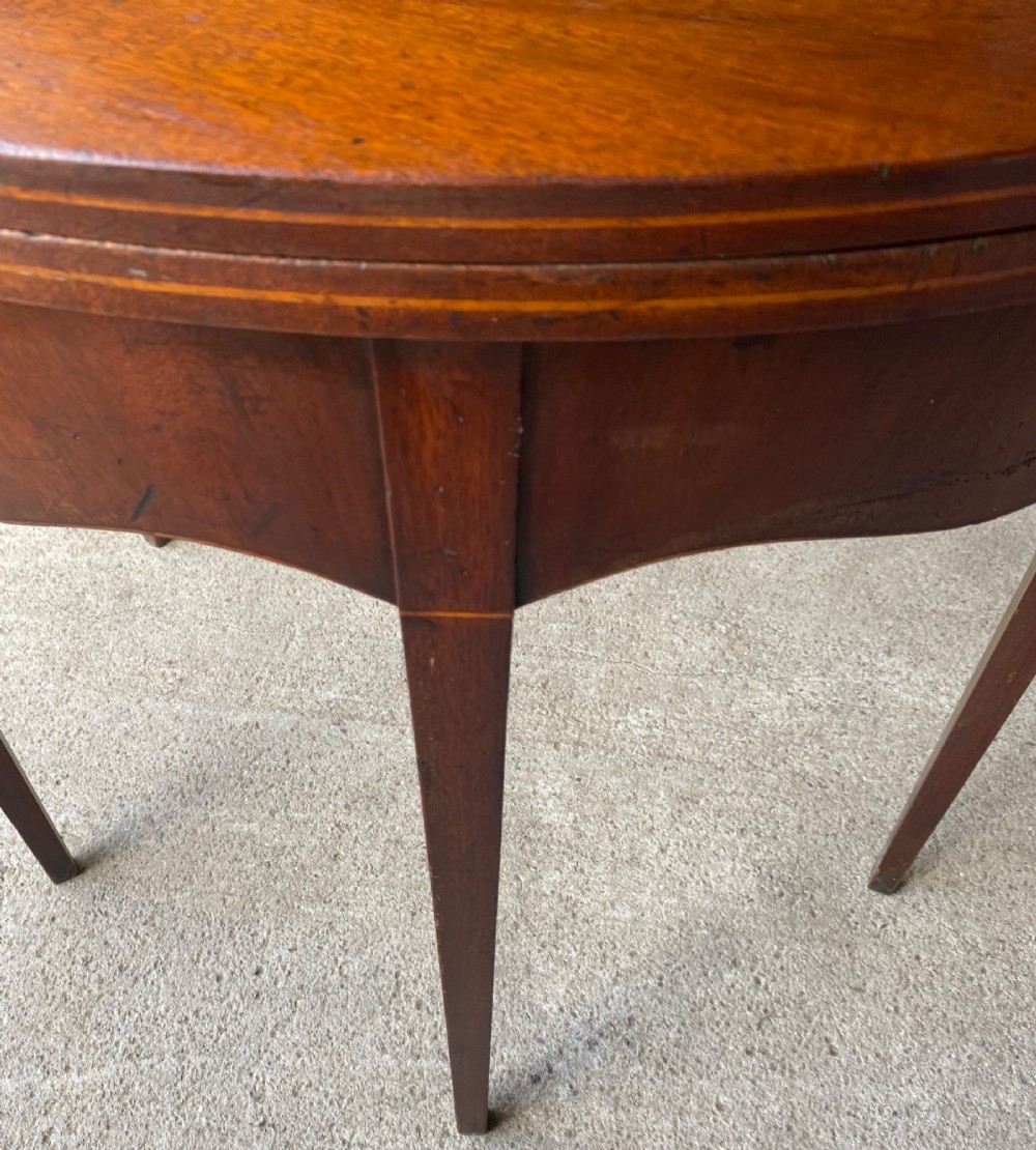 An 18th-century mahogany demilune tea table featuring a semi-circular fold-over top and four slender tapered legs. View II