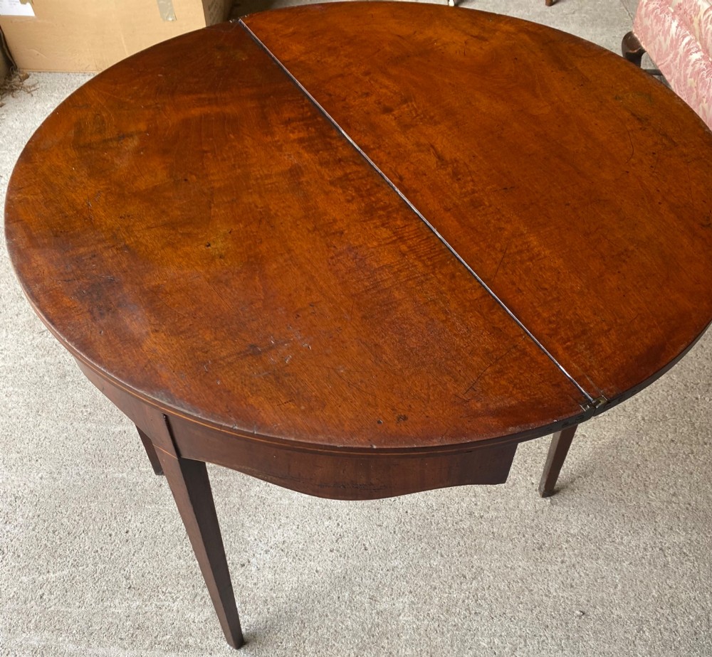 An 18th-century mahogany demilune tea table featuring a semi-circular fold-over top and four slender tapered legs. View V