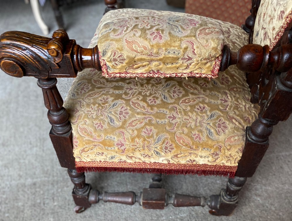 A 19th-century carved dark oak armchair with an oval upholstered backrest, ornate leaf cresting, and scrolled armrests. View IV