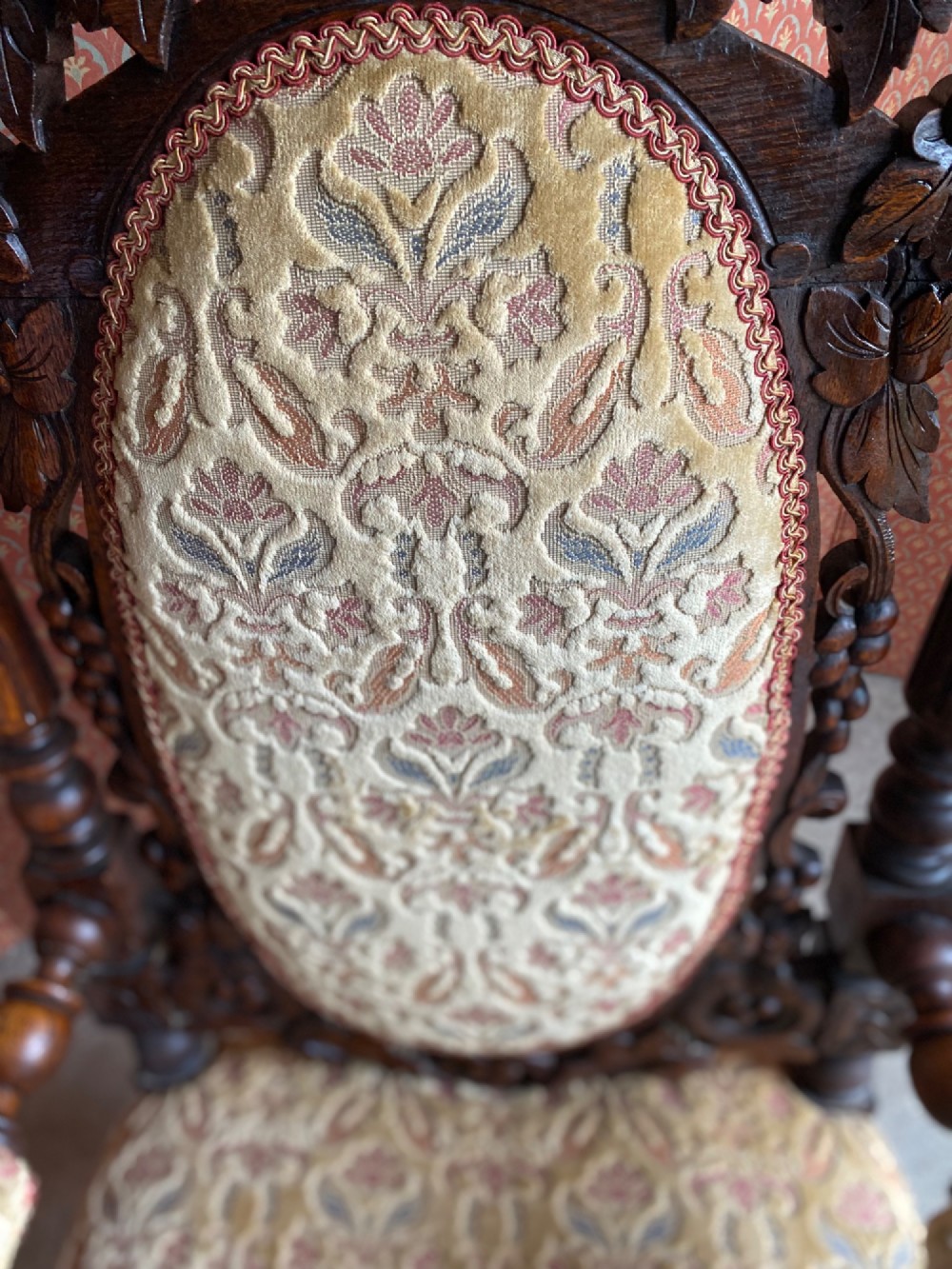 A 19th-century carved dark oak armchair with an oval upholstered backrest, ornate leaf cresting, and scrolled armrests. View V