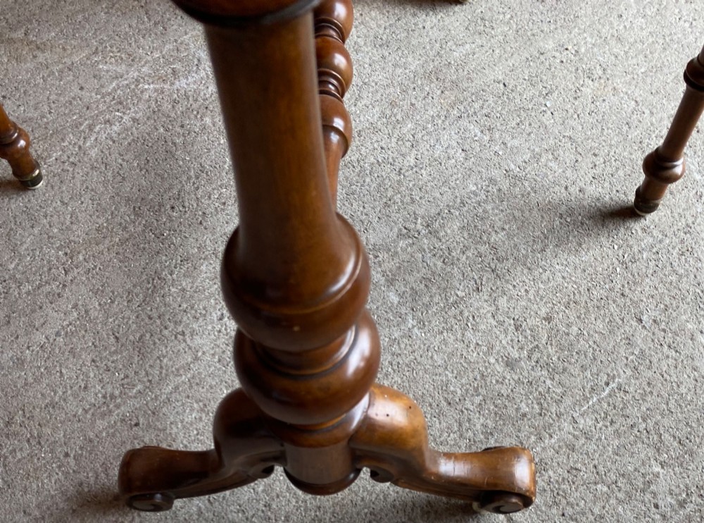 A Victorian burr walnut drop leaf table with turned twin column supports, a stretchered base, scrolled feet on brass castors, and a figured veneer surface. View V