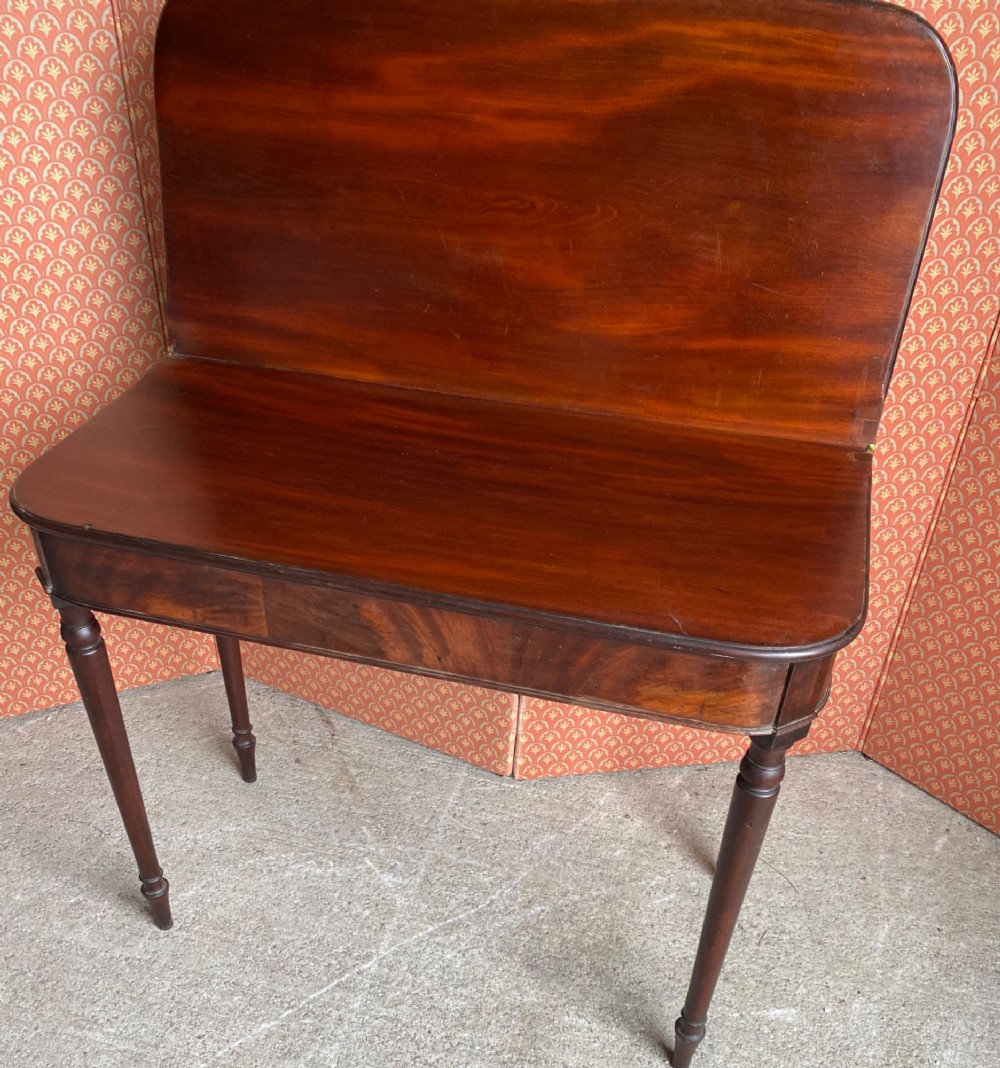 An 18th-century Cuban mahogany tea table featuring a polished foldover top, rounded corners, a deep apron, and slender turned legs. View II