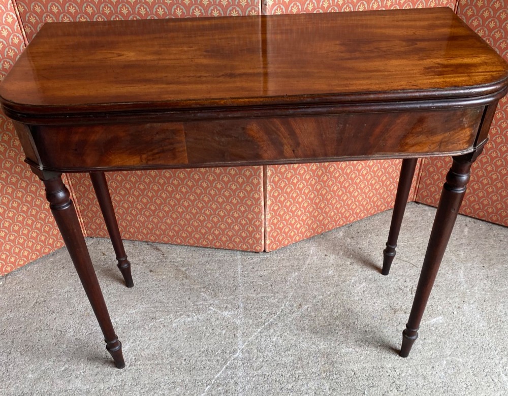 An 18th-century Cuban mahogany tea table featuring a polished foldover top, rounded corners, a deep apron, and slender turned legs. View III