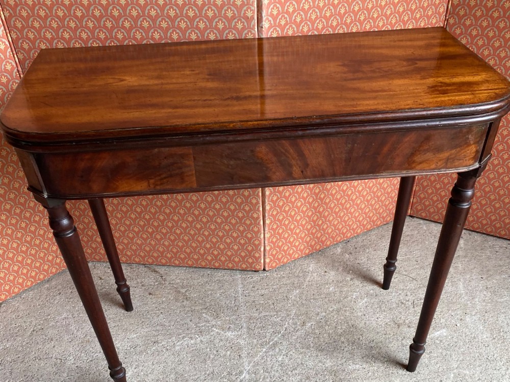 An 18th-century Cuban mahogany tea table featuring a polished foldover top, rounded corners, a deep apron, and slender turned legs. View IV