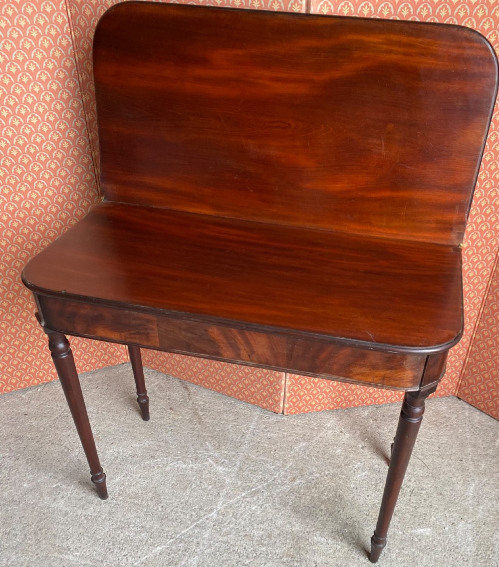 An 18th-century Cuban mahogany tea table featuring a polished foldover top, rounded corners, a deep apron, and slender turned legs. View V