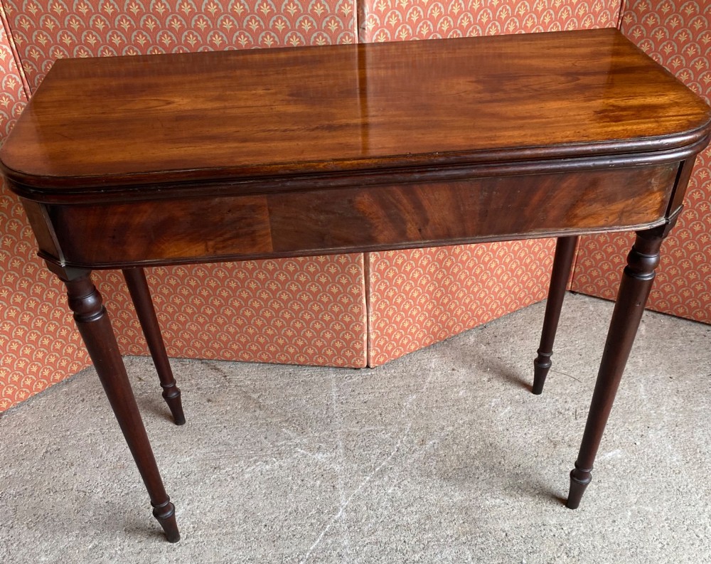 An 18th-century Cuban mahogany tea table featuring a polished foldover top, rounded corners, a deep apron, and slender turned legs. View VI