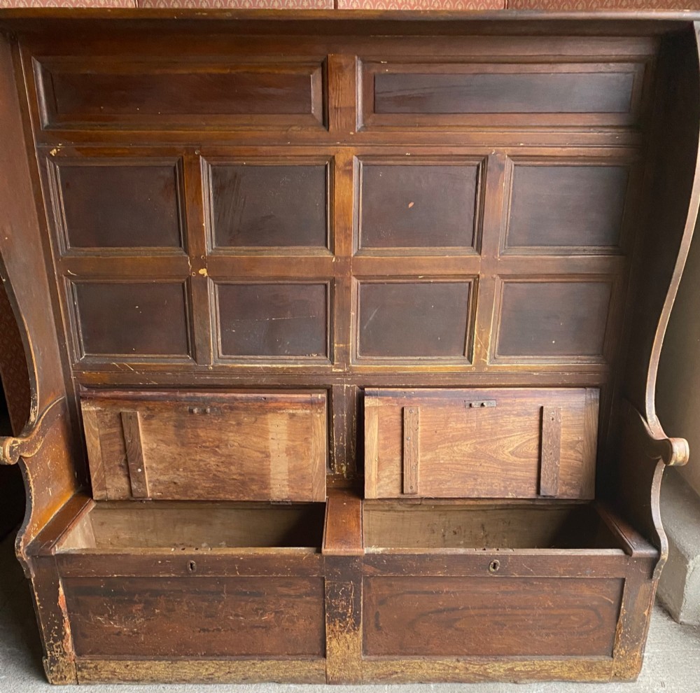 An 18th-century high-backed wooden settle featuring multi-panelled backboards, wing sides, and a lift-up box seat base with rich brown patina. View II