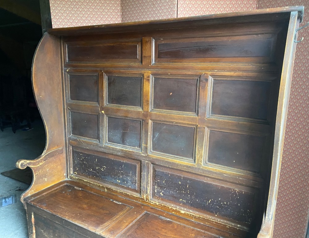 An 18th-century high-backed wooden settle featuring multi-panelled backboards, wing sides, and a lift-up box seat base with rich brown patina. View III
