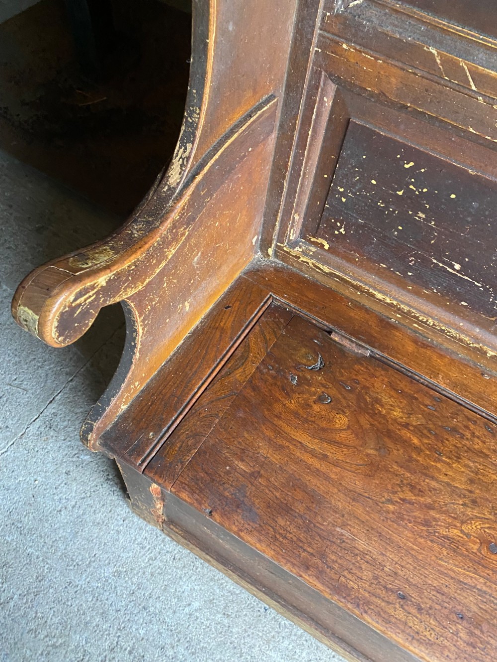 An 18th-century high-backed wooden settle featuring multi-panelled backboards, wing sides, and a lift-up box seat base with rich brown patina. View VI