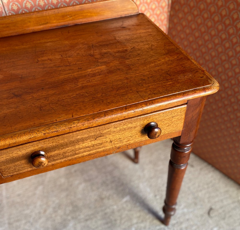 A Victorian warm brown mahogany writing desk featuring two frieze drawers with turned wooden knobs, supported by turned tapered legs and a low gallery backboard. View III