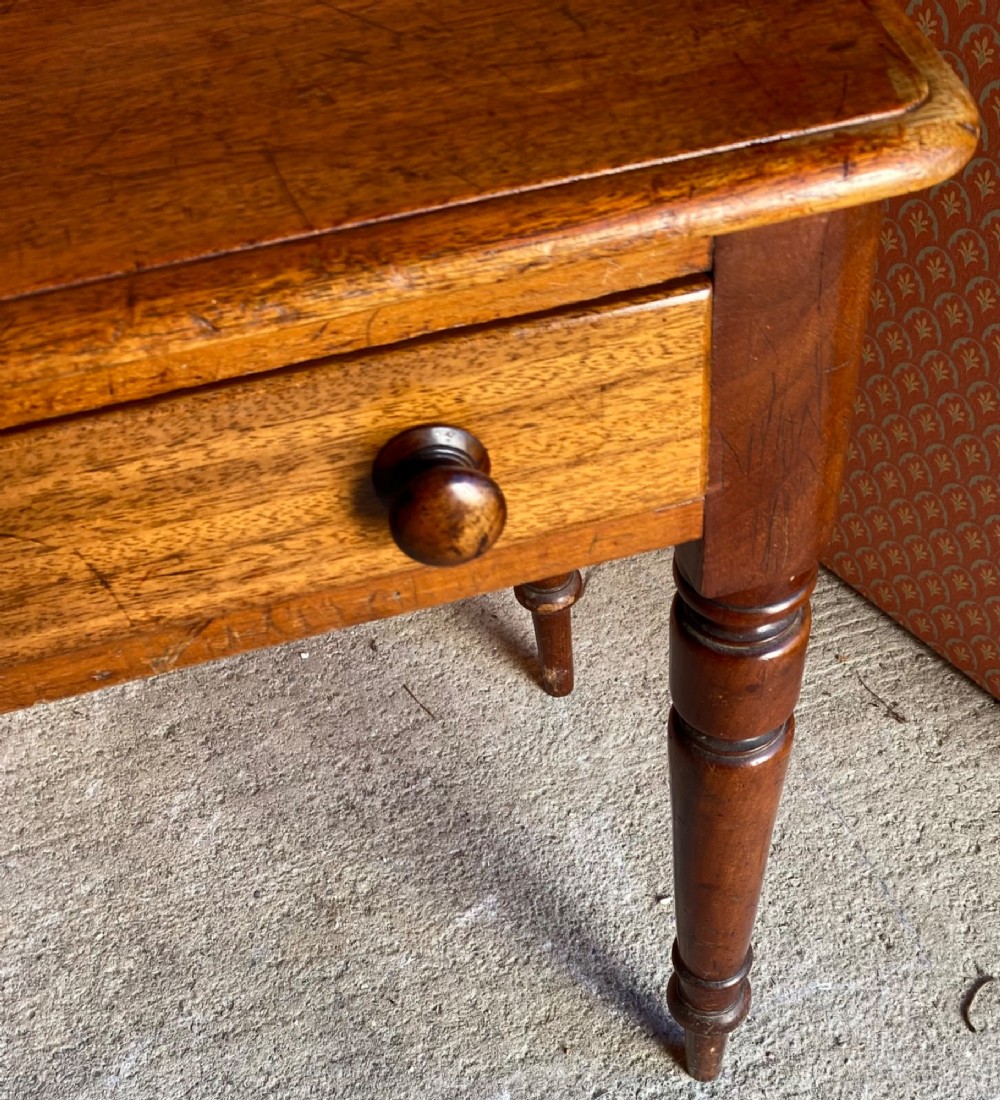 A Victorian warm brown mahogany writing desk featuring two frieze drawers with turned wooden knobs, supported by turned tapered legs and a low gallery backboard. View V