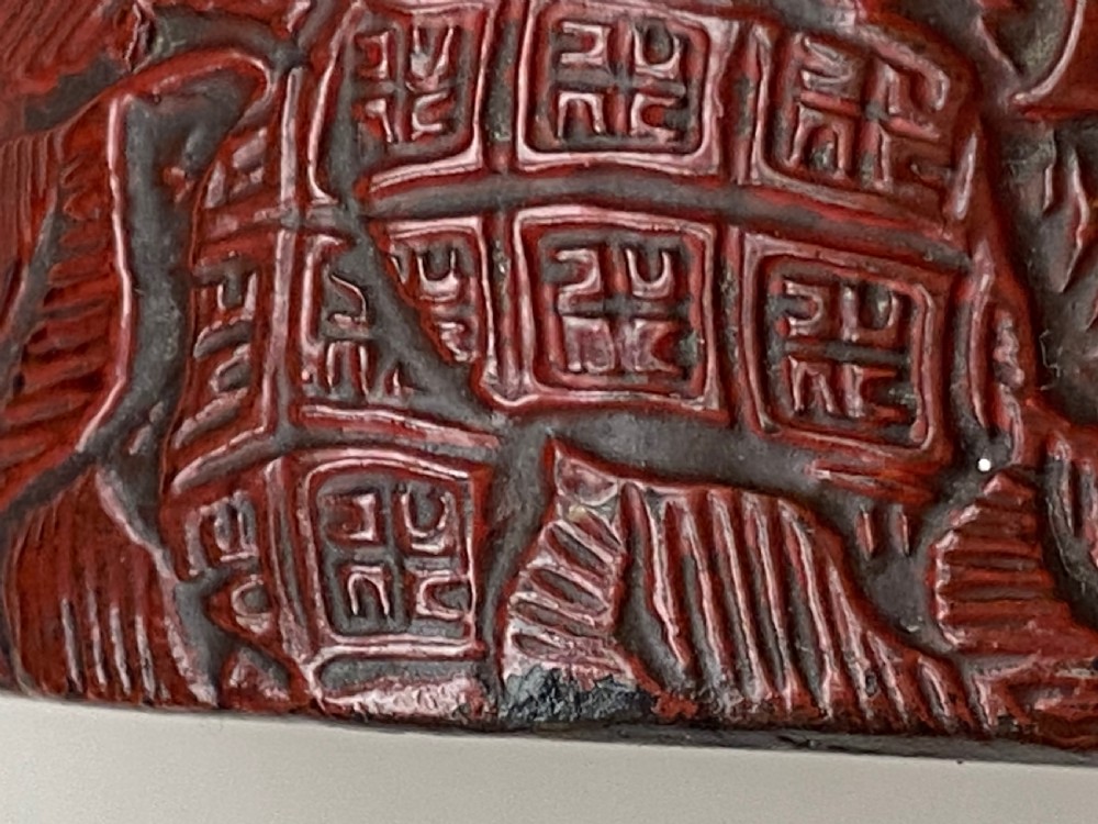 A lobed Qing Dynasty carved red cinnabar lacquer lidded box decorated with chrysanthemum blossoms and rockwork over a dark diaper background. View V