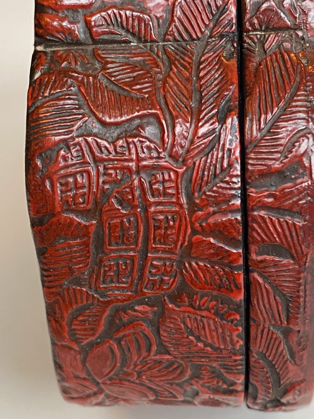 A lobed Qing Dynasty carved red cinnabar lacquer lidded box decorated with chrysanthemum blossoms and rockwork over a dark diaper background. View XI