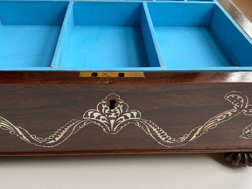 A Regency rosewood workbox with mother-of-pearl foliate inlays, side ring handles, and carved feet. View IX