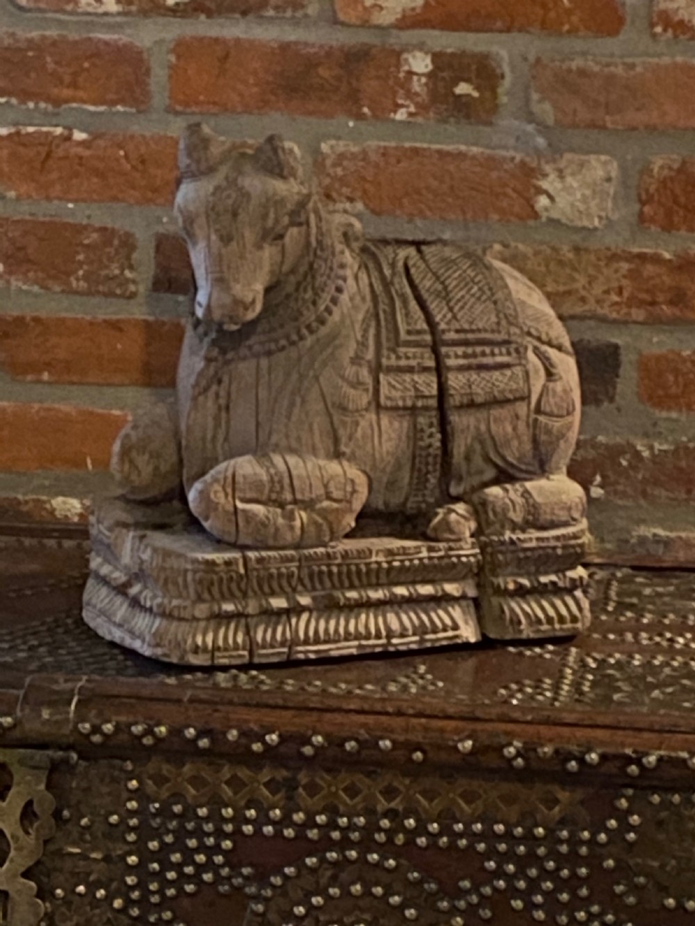 A carved wooden sculpture of a seated Nandi bull on a decorated plinth featuring intricate neck garlands and a saddle cover. View III