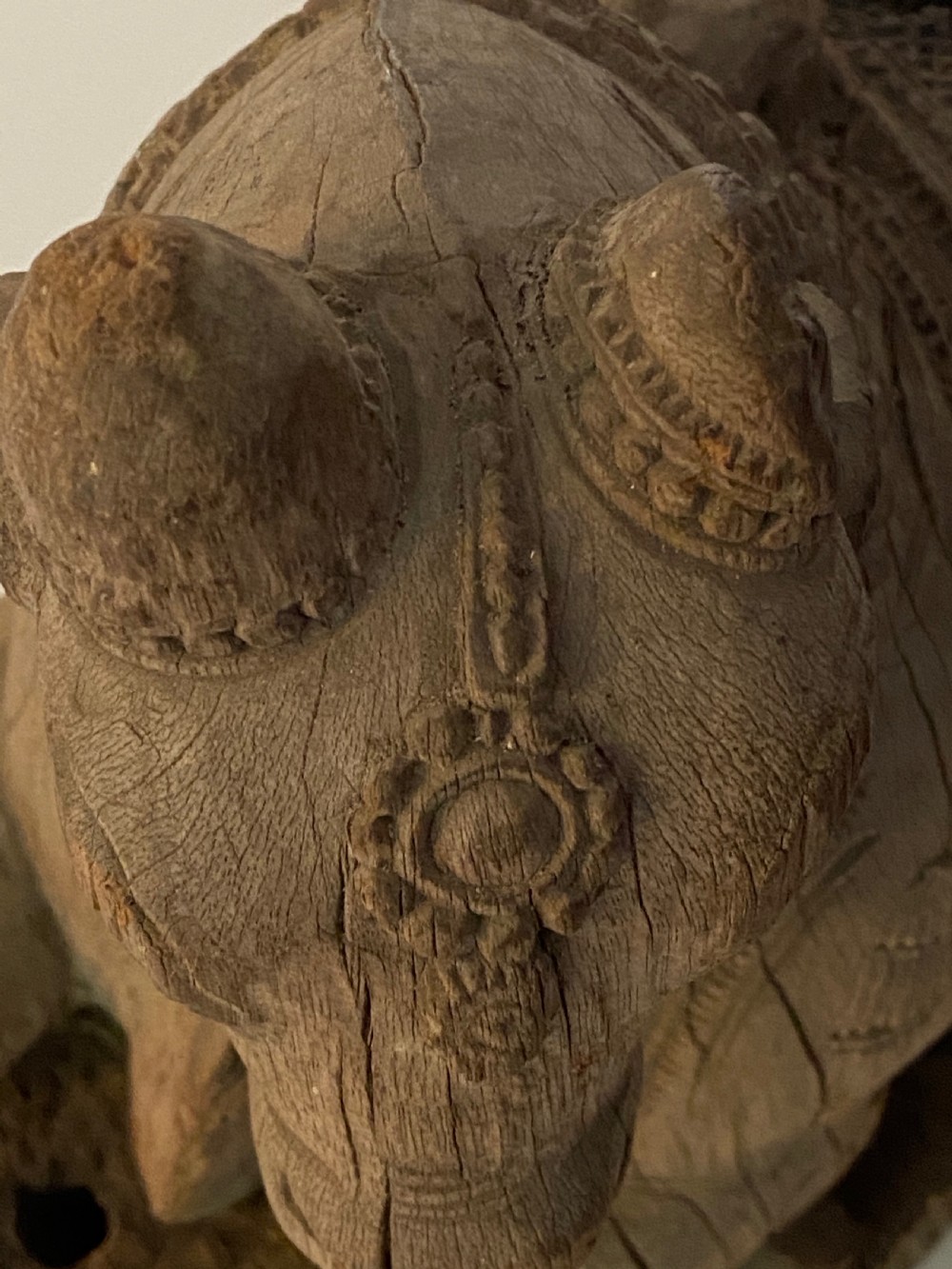 A carved wooden sculpture of a seated Nandi bull on a decorated plinth featuring intricate neck garlands and a saddle cover. View V
