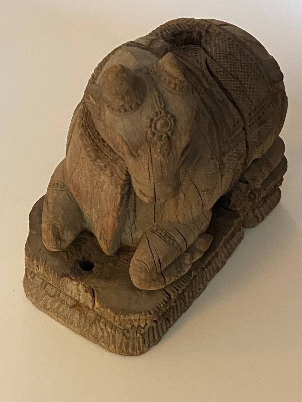 A carved wooden sculpture of a seated Nandi bull on a decorated plinth featuring intricate neck garlands and a saddle cover. View XIII