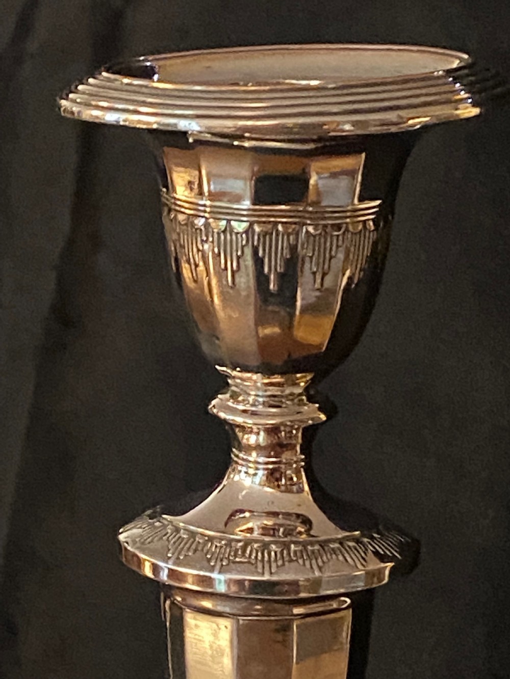 A pair of George III silver-plated candlesticks featuring faceted tapering shafts and circular stepped bases holding white candles. View IX