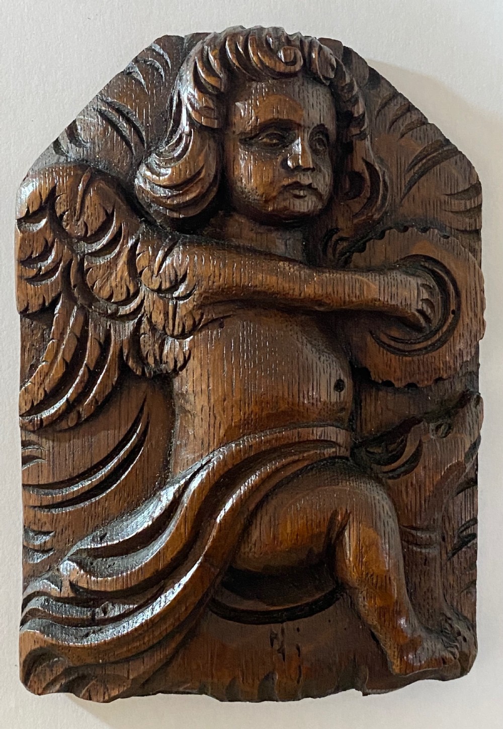 A pair of dark carved oak relief panels depicting winged cherubs playing musical instruments. View VI