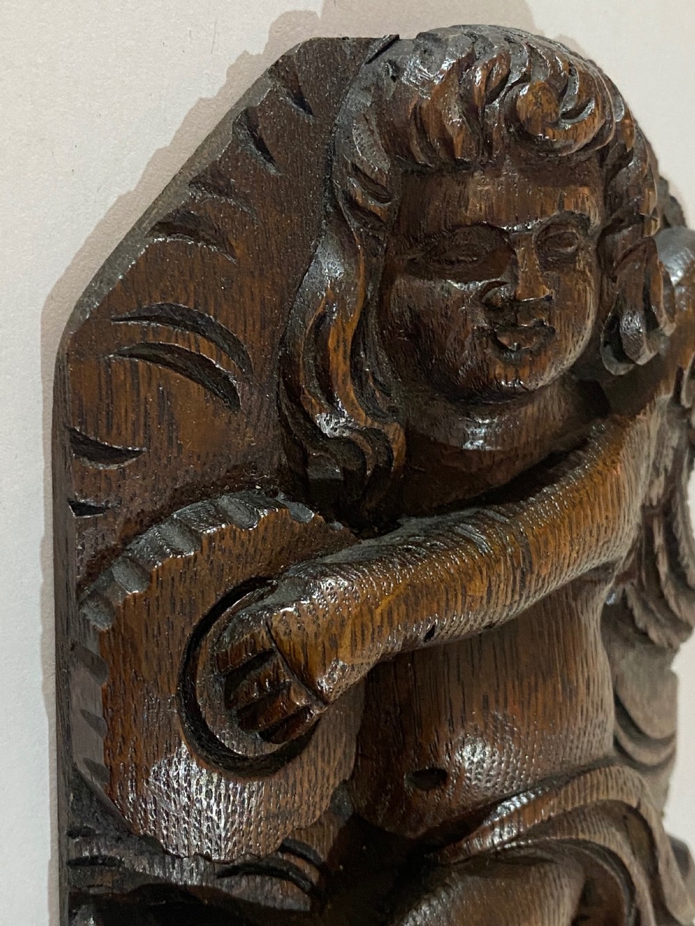 A pair of dark carved oak relief panels depicting winged cherubs playing musical instruments. View VII