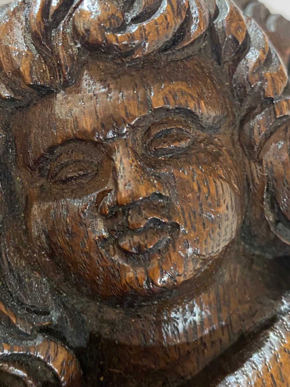 A pair of dark carved oak relief panels depicting winged cherubs playing musical instruments. View VIII