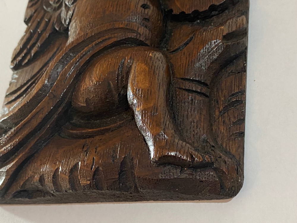 A pair of dark carved oak relief panels depicting winged cherubs playing musical instruments. View IX