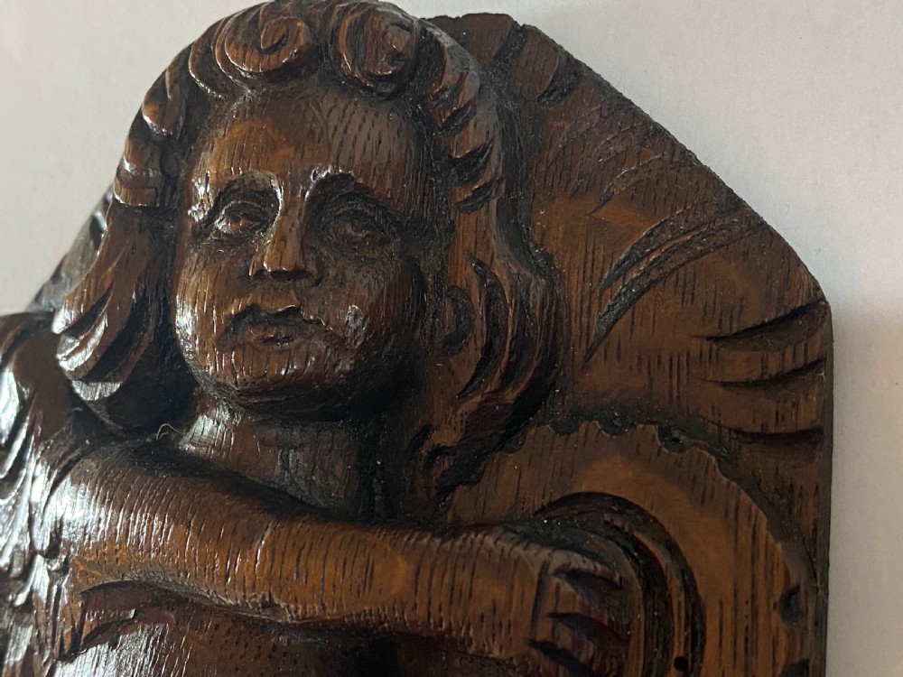 A pair of dark carved oak relief panels depicting winged cherubs playing musical instruments. View X