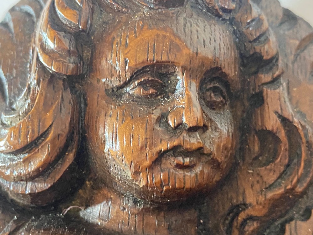 A pair of dark carved oak relief panels depicting winged cherubs playing musical instruments. View XI