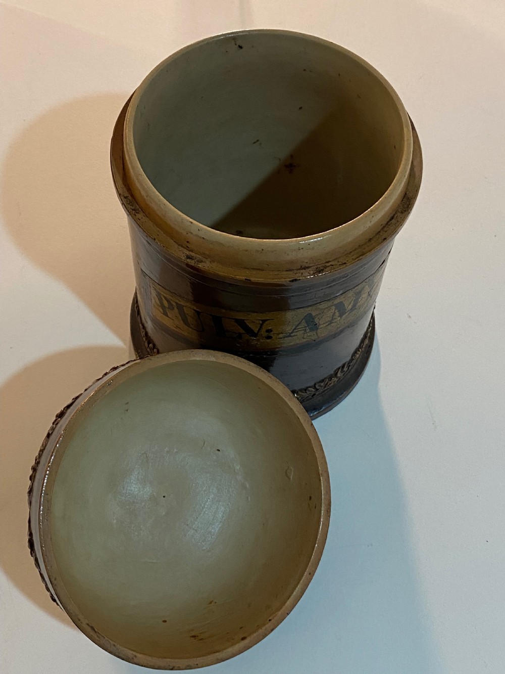 A mid-19th century brown glazed stoneware apothecary jar featuring floral relief borders and a label reading PULV AMYLI. View VI