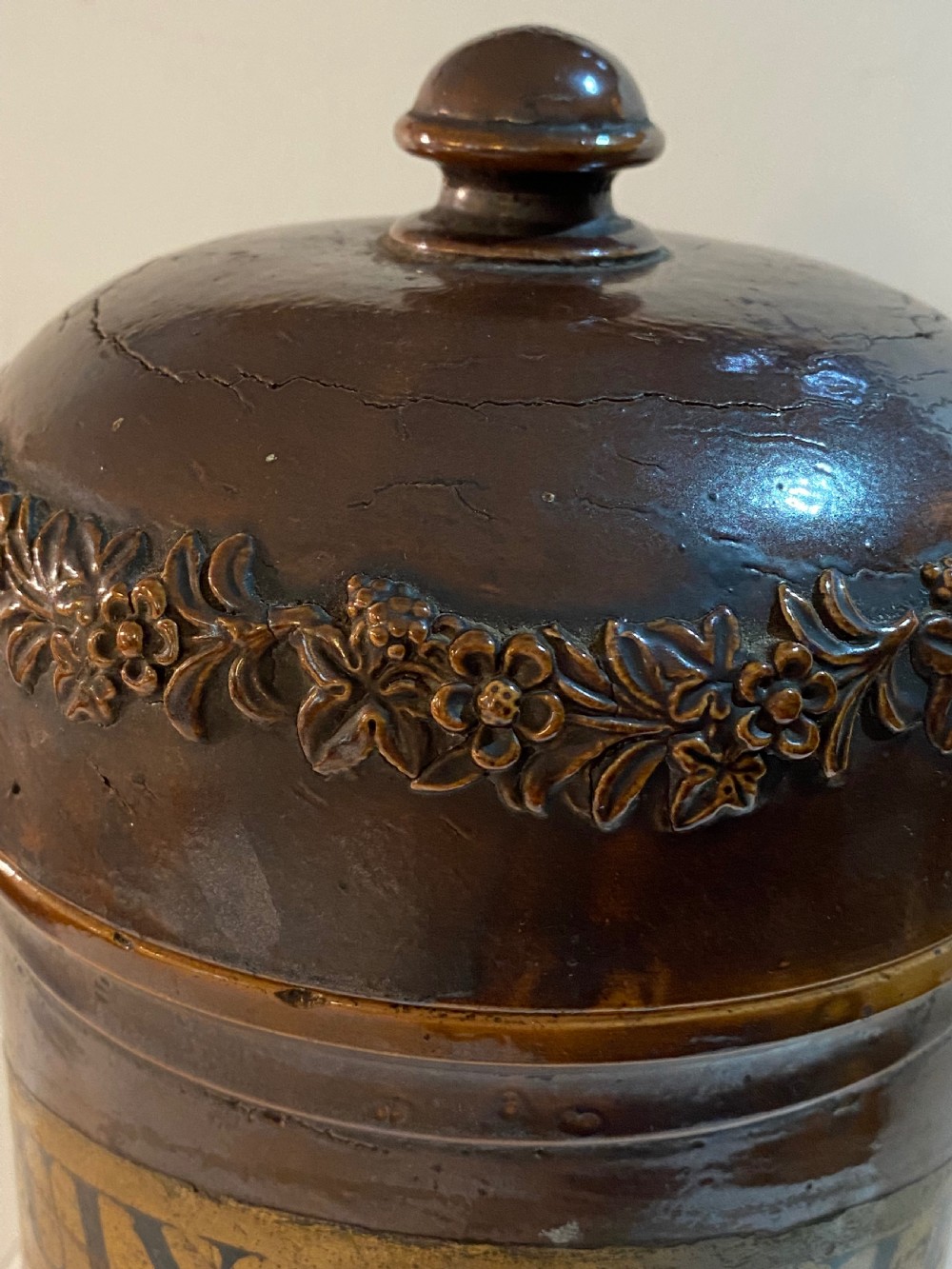 A mid-19th century brown glazed stoneware apothecary jar featuring floral relief borders and a label reading PULV AMYLI. View X