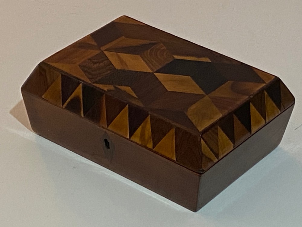 A rectangular wooden box featuring geometric parquetry inlay in contrasting shades of brown wood with a keyhole on the front. View II