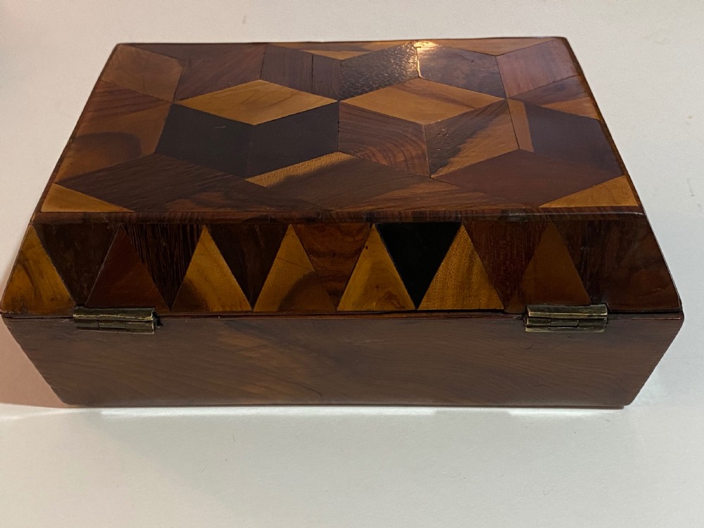 A rectangular wooden box featuring geometric parquetry inlay in contrasting shades of brown wood with a keyhole on the front. View XII