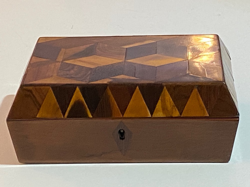 A rectangular wooden box featuring geometric parquetry inlay in contrasting shades of brown wood with a keyhole on the front. View XIII
