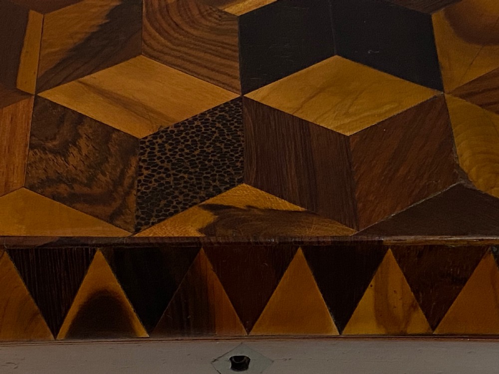 A rectangular wooden box featuring geometric parquetry inlay in contrasting shades of brown wood with a keyhole on the front. View XIV