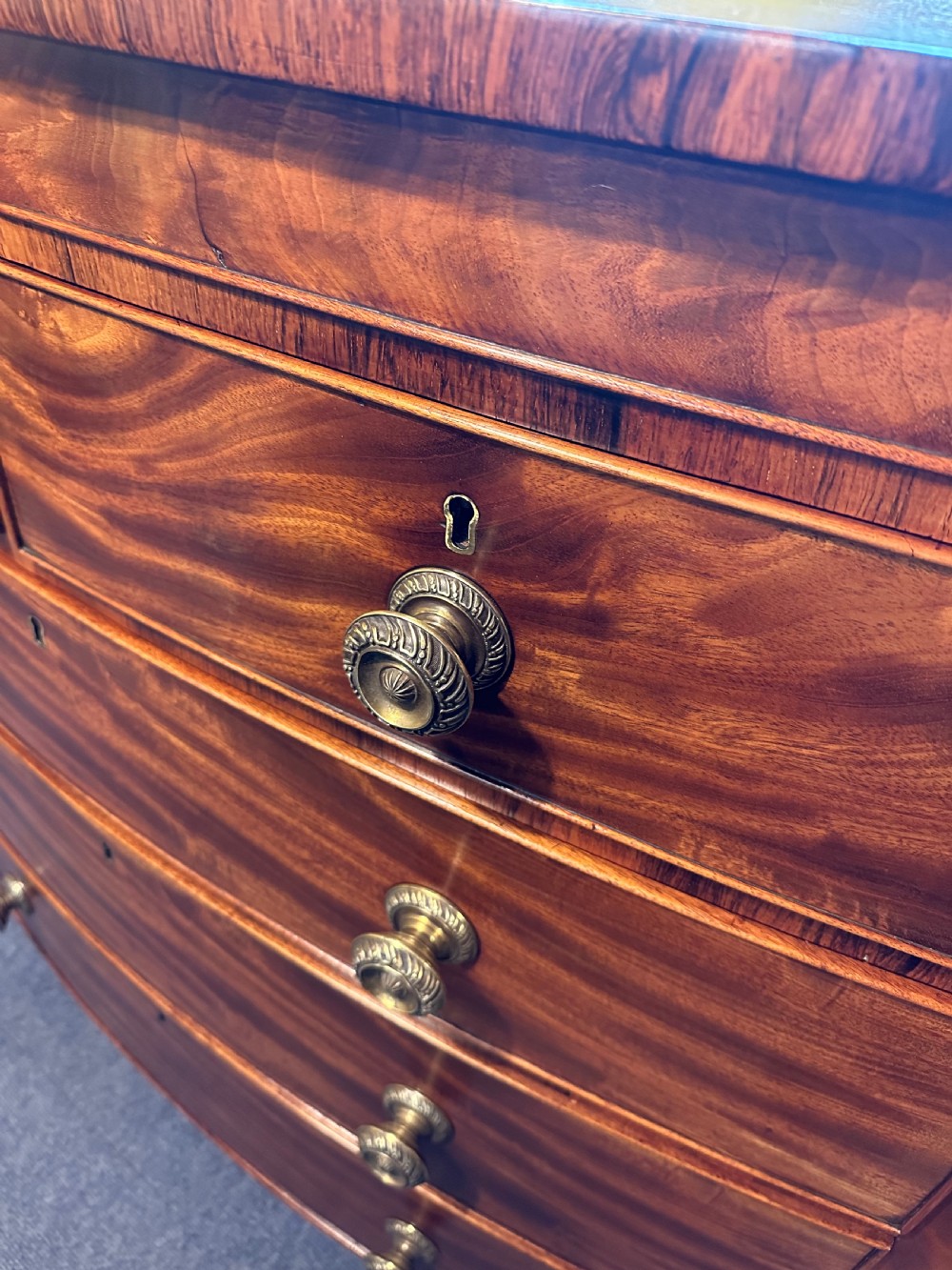 A large Regency mahogany bowfront chest featuring two short over three long graduated drawers with decorative brass turned handles on splayed feet. View III