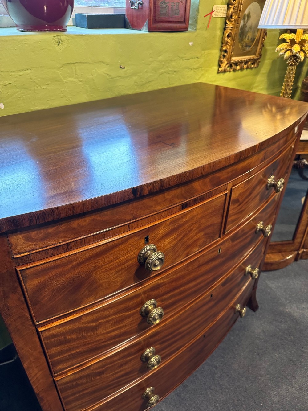 A large Regency mahogany bowfront chest featuring two short over three long graduated drawers with decorative brass turned handles on splayed feet. View IX