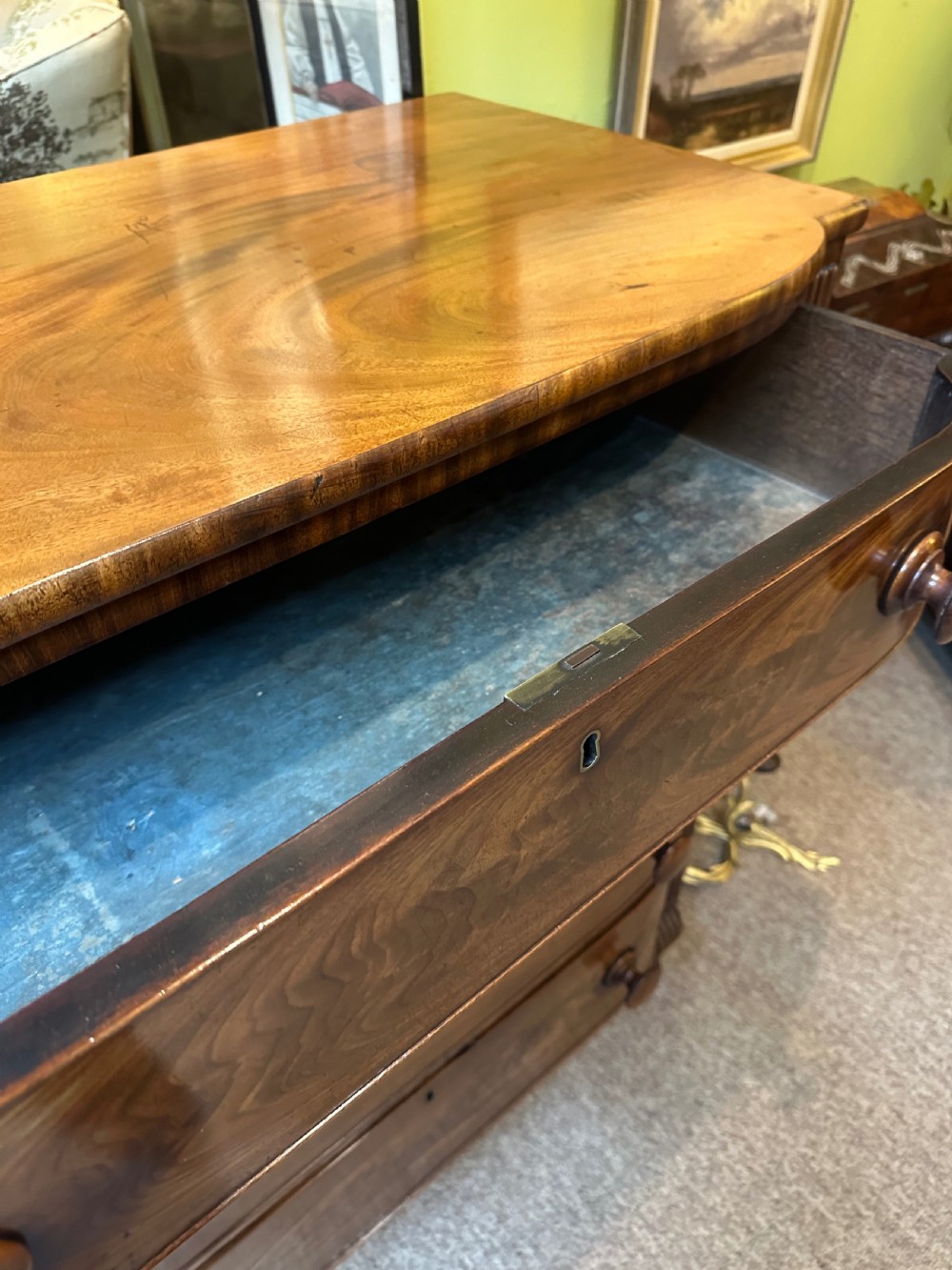 A Regency flame mahogany chest of drawers featuring four graduated bow-front drawers, turned wood handles, and reeded side columns. View VI