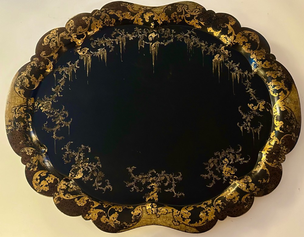 Large Victorian black papier-mache tray by Jennens and Bettridge featuring scalloped edges and detailed gilt scrollwork.