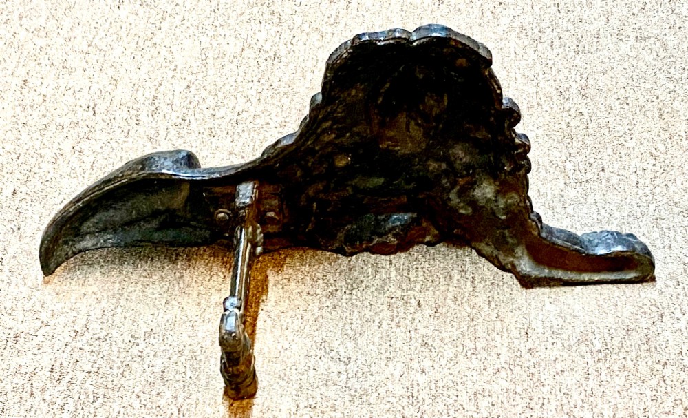 A heavy black cast iron figure depicting a recumbent lion, designed as a boot scraper or doorstop. View III