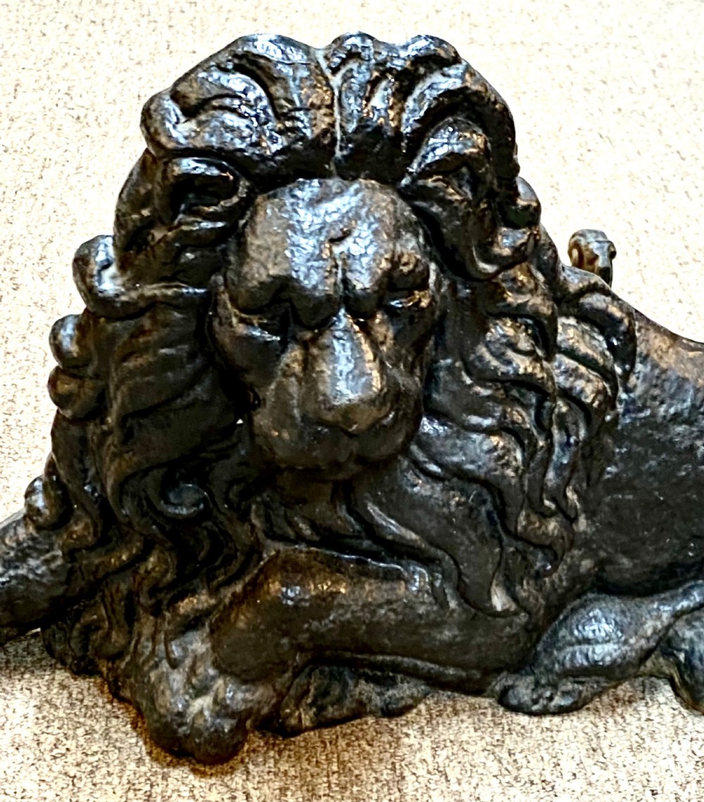 A heavy black cast iron figure depicting a recumbent lion, designed as a boot scraper or doorstop. View II