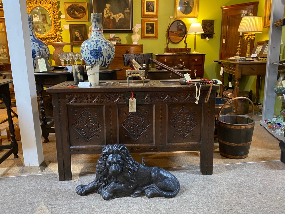 A heavy black cast iron figure depicting a recumbent lion, designed as a boot scraper or doorstop. View V